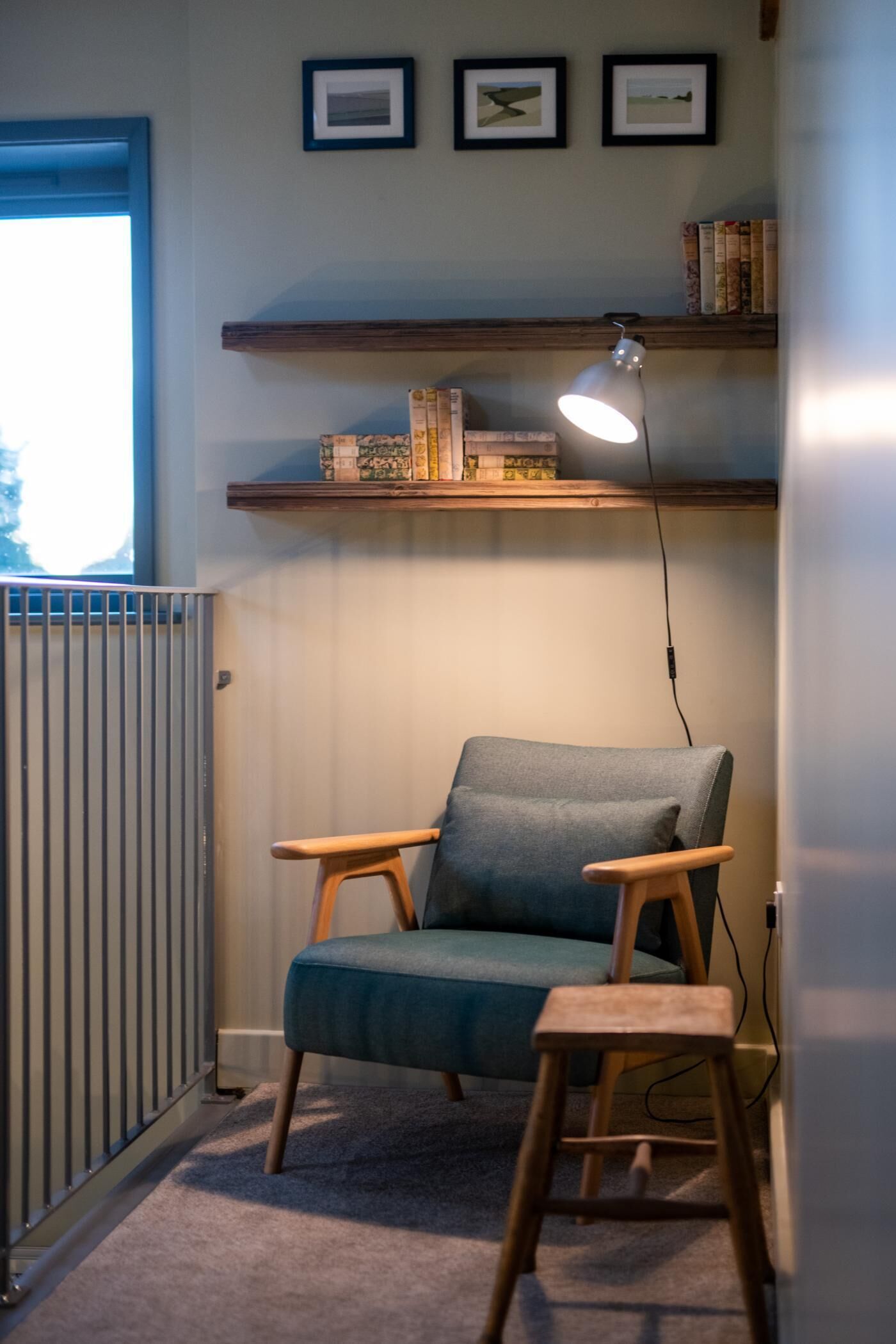 Una stanza con una sedia blu, una scrivania, un termosifone ed scaffali con libri e una lampada.