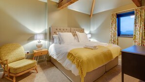 A bedroom with a bed, a chair, a nightstand, a window with curtains, and exposed wooden beams. - 3 Bed in Holme-on-Spalding-Moor (oc-vy213) (Holme-on-Spalding-Moor)