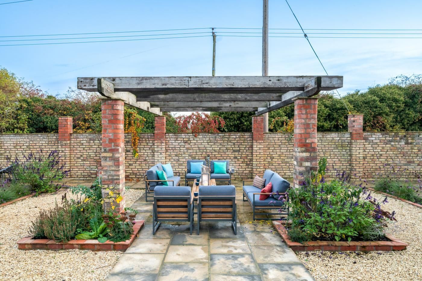 A patio with outdoor furniture, a pergola, and a brick wall.