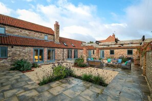 A courtyard with stone flooring, brick buildings, and outdoor seating. - 7 Bed in Holme-on-Spalding-Moor (oc-vy216) (Holme-on-Spalding-Moor)