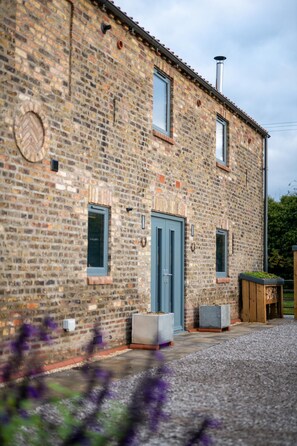A stone building with a blue door, windows, and a chimney. - 2 Bed in Holme-on-Spalding-Moor (oc-vy214) (Holme-on-Spalding-Moor)