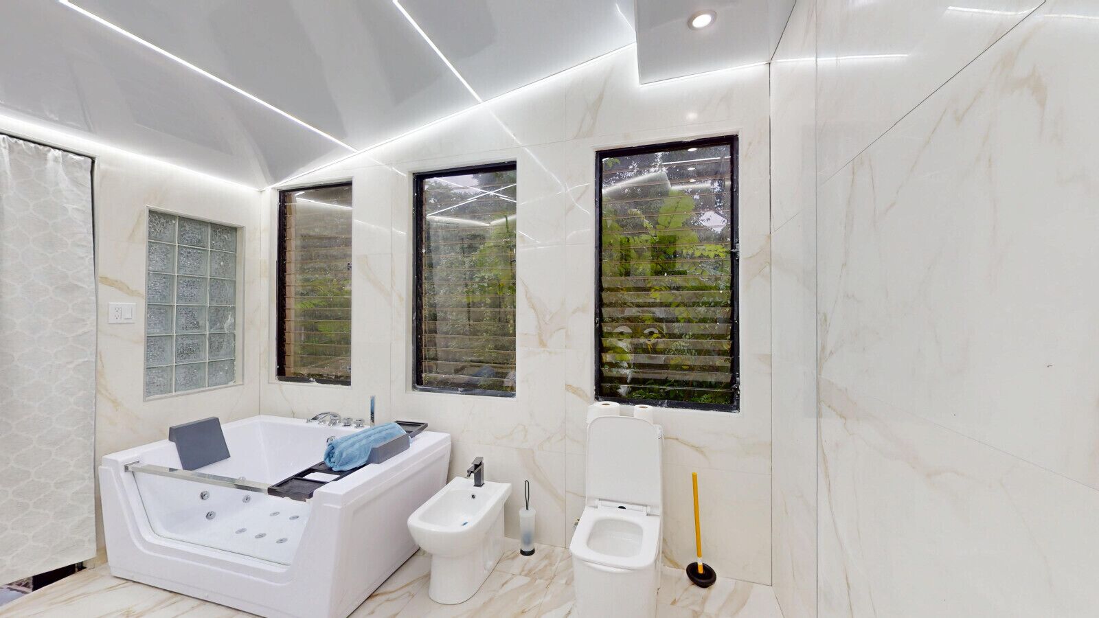 A modern bathroom with a bathtub, bidet, and large windows.