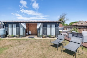 A house with a front door, two sliding glass doors, a patio with outdoor furniture, and a water tank. - 8 Bed in Bacton (oc-2383) (Bacton)