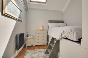 A bedroom with a loft bed, a bedside table with a lamp, a radiator, and a framed picture on the wall. - 8 Bed in Bacton (oc-2383) (Bacton)