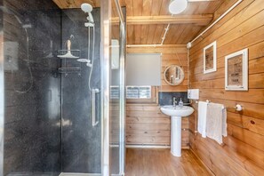 A wooden interior with a glass shower enclosure, a sink, and framed quotes on the wall. - 8 Bed in Bacton (oc-2383) (Bacton)