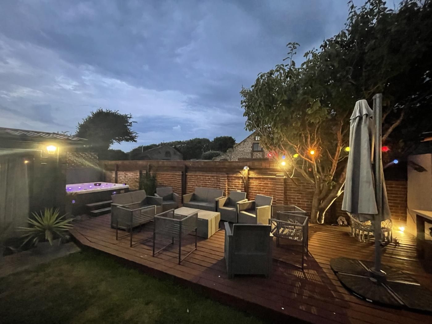 A backyard with outdoor seating, a hot tub, and string lights.