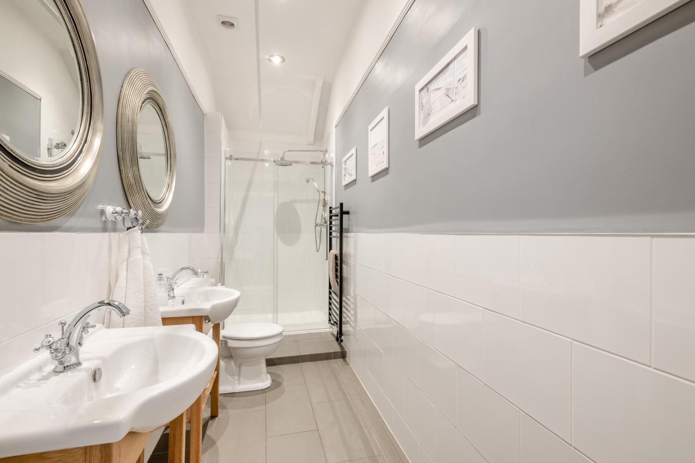 A modern bathroom with two sinks, a toilet, and a shower.
