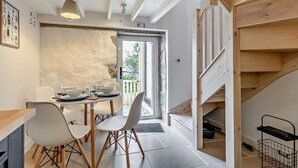 Eine moderne Küche mit Essbereich, einer Holztreppe und Blick ins Freie.