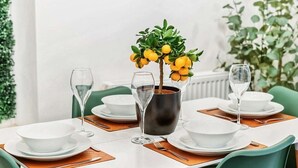 A dining table set with white plates, bowls, and cutlery, accompanied by a vase with yellow flowers and a metal bucket. - 4 Bed townhouse Swansea city centre (Swansea)