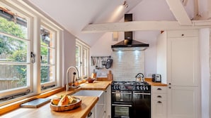 A kitchen with a large island, a gas stove, oven, and a hanging pot rack. - 3 Bed in Benenden (oc-cb671) (Benenden)