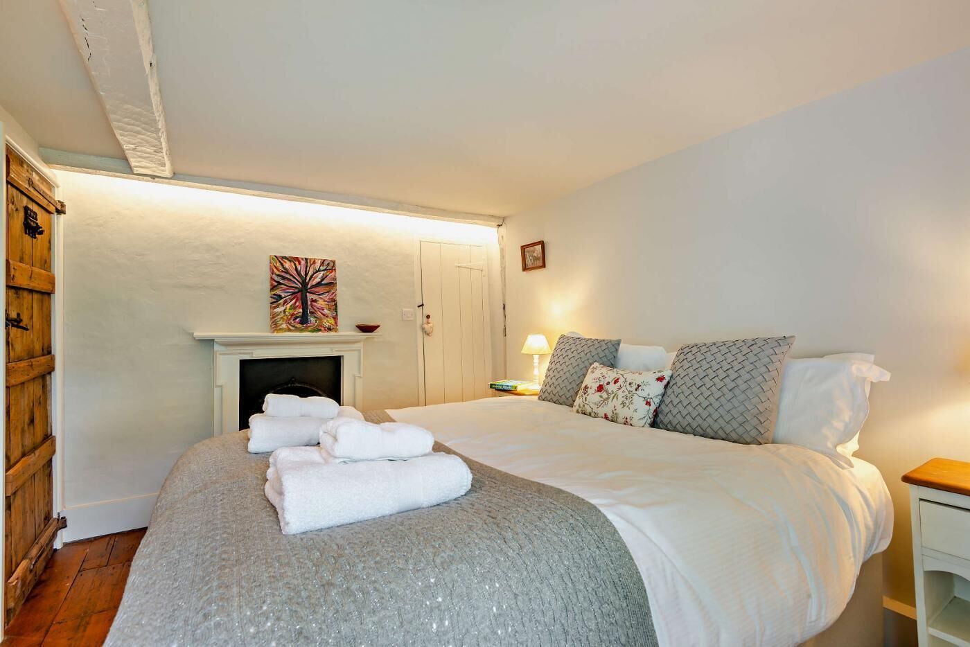A bedroom with a bed, a fireplace, and a nightstand.