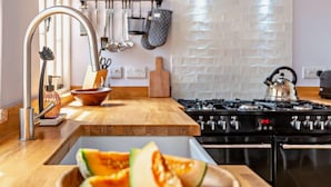 A modern kitchen with a wooden countertop, a gas stove, and a bowl of cantaloupe. - 3 Bed in Benenden (oc-cb671) (Benenden)