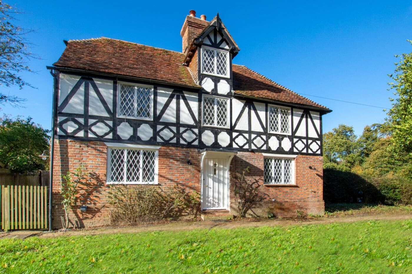 Ein Haus im Tudor-Stil mit Backsteinfassade, weißem Fachwerk und einem steilen Satteldach.