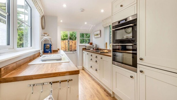 A modern kitchen with white cabinetry, a wooden countertop, and stainless steel appliances. - 2 Bed in Holt (oc-2377) (Holt)