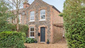 A two-story house with a stone facade, a black front door, and a small front garden. - 2 Bed in Holt (oc-2377) (Holt)