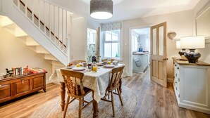 A dining area with a table set for two, a staircase, a kitchen in the background, and a laundry room. - 2 Bed in Holt (oc-2377) (Holt)