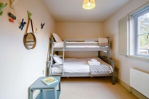 Une chambre avec un lit superposé, une petite table et une fenêtre.