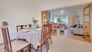 Un comedor con una mesa dispuesta para cuatro personas, un sofá y vistas al exterior.