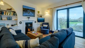 A living room with a fireplace, a television, a sofa, and a bookshelf. - 2 Bed in Morston (oc-2382) (Morston)