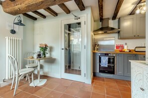 Una cucina con una porta bianca, un tavolo da pranzo con sedie e un pavimento piastrellato.