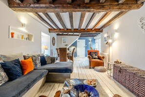 A cozy living room with a wooden ceiling, a sofa set, a dining area, and a wicker chair. - 3 Bed in Brancaster (oc-h27159) (Brancaster)