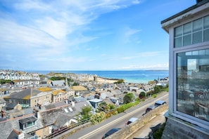 A coastal town with historic buildings, a clear view of the sea, and a road with vehicles. - 2 Bed in St. Ives (oc-s27148) (Saint Ives)
