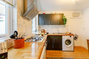 Eine moderne Küche mit Gasherd, integriertem Waschmaschine und einem Fenster für natürliches Licht.