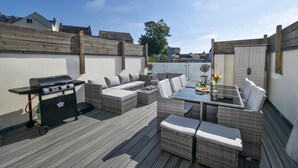 An outdoor patio with a grill, wicker furniture, and a dining table. - 4 Bed in Saundersfoot (oc-pw9285) (Saundersfoot)