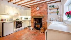 A kitchen with white cabinets, a brick fireplace, a stove, and a sink. - 2 Bed in Weybourne (oc-2372) (Weybourne)