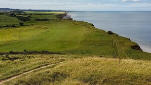 A coastal landscape with a grassy field and a path leading to the beach. - 2 Bed in Weybourne (oc-2372) (Weybourne)