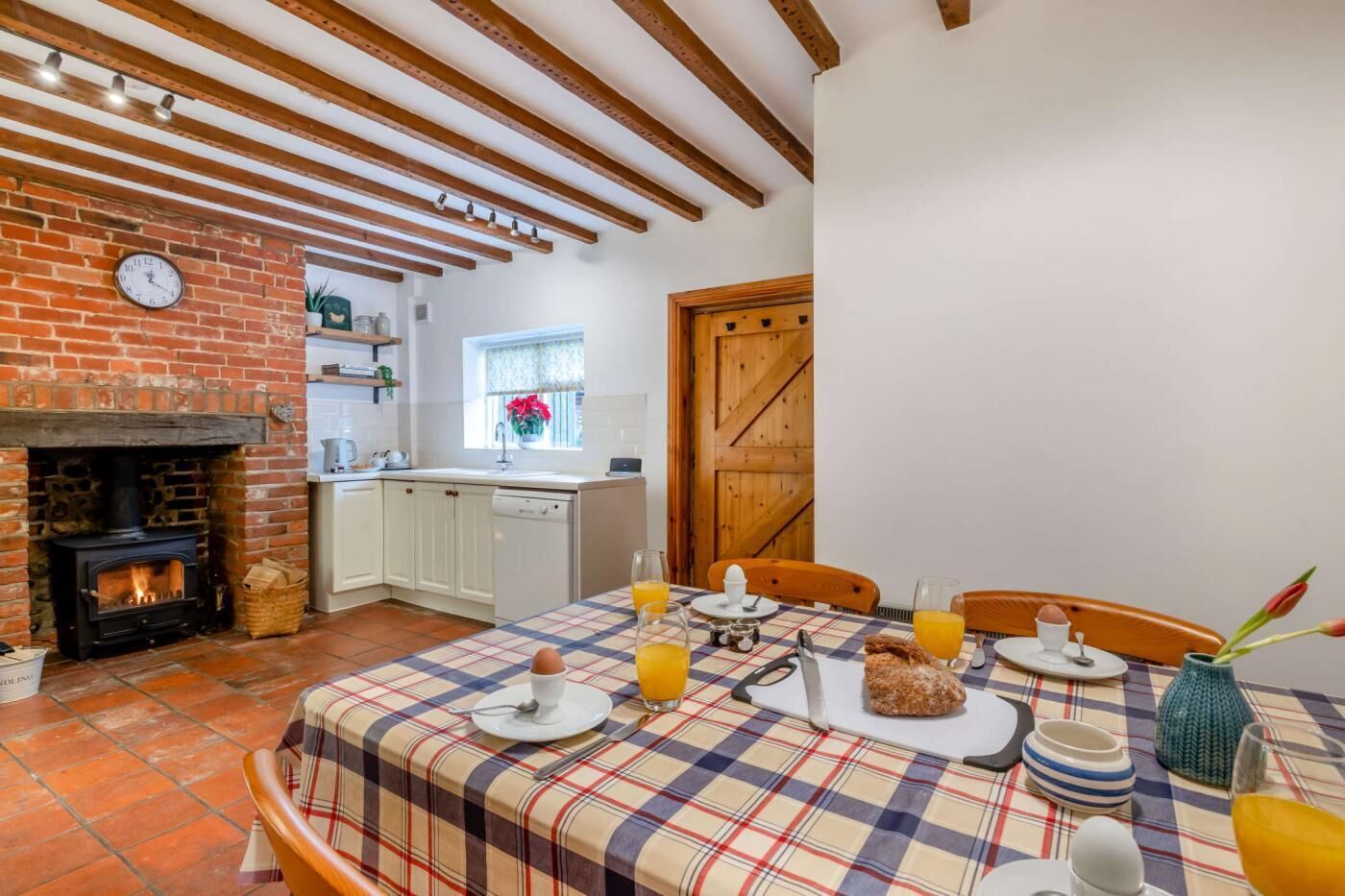 Una cocina acogedora con chimenea, una mesa de comedor lista para el desayuno y una puerta de madera.