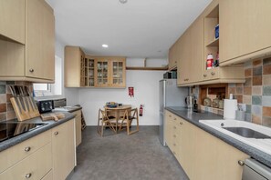 Cocina compacta con armarios de madera, una mesa de comedor y un refrigerador.