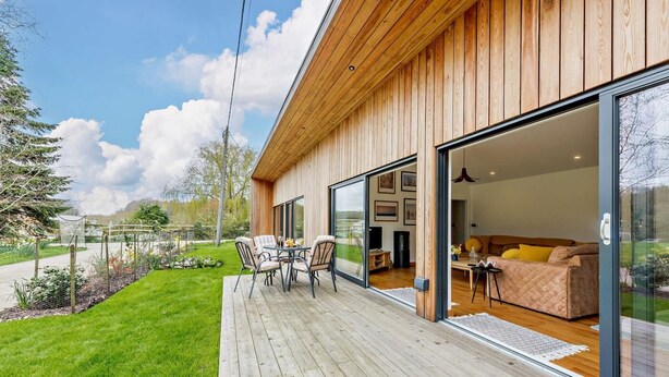 A modern house with a wooden deck, large sliding glass doors leading to a living area with a sofa and coffee table. - 2 Bed in Beckley (oc-rh1176) (Beckley)