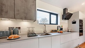 A modern kitchen with white cabinets, a built-in oven, a toaster, and a bread loaf on the counter.