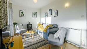 A living room with a sofa, chairs, a coffee table, and a radiator. - 2 Bed in Eccles-on-Sea (oc-a27194) (Eccles-on-Sea)
