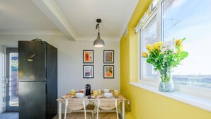 A kitchen with a dining table, chairs, a refrigerator, and a window with a view. - 2 Bed in Eccles-on-Sea (oc-a27194) (Eccles-on-Sea)