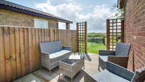 A patio with wicker furniture, a wooden fence, and a view of a brick building. - 2 Bed in Eccles-on-Sea (oc-a27194) (Eccles-on-Sea)