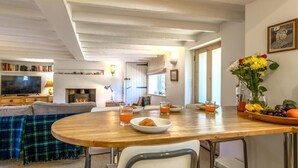Una sala de estar acogedora con chimenea, una mesa de comedor con sillas, un sofá y una televisión.