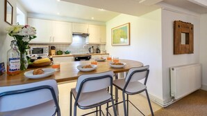 Una cocina moderna con armarios blancos, una mesa de comedor de madera y un radiador.
