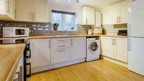 Une cuisine moderne avec des meubles blancs, un lave-linge encastré et un four à micro-ondes.