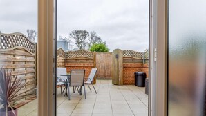 Un espace extérieur aménagé avec une table et des chaises, une clôture en bois et une poubelle.