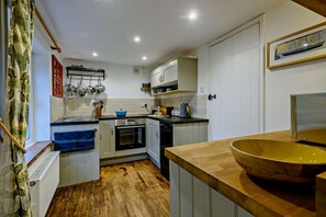 Eine kleine Küche mit weißen Schränken, einer Holz Arbeitsplatte und einer großen Schüssel.