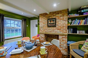 Un comedor con pared de ladrillo, estantería y vistas al exterior.