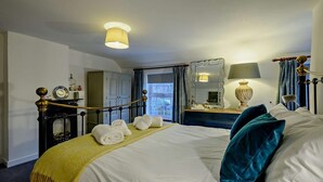 Ein Hotelzimmer mit Bett, Nachttischen, einem Spiegel, einer Lampe und Blick ins Freie.