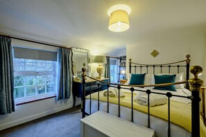 Ein Bett mit Baldachin, ein Nachttisch mit Lampe und ein Fenster mit Vorhängen.