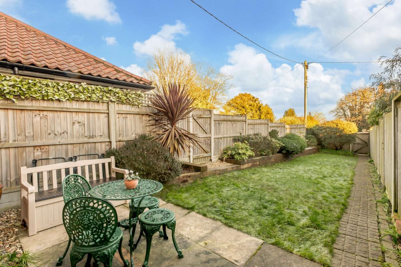 A backyard with a wooden fence, a lawn, and a table with chairs.