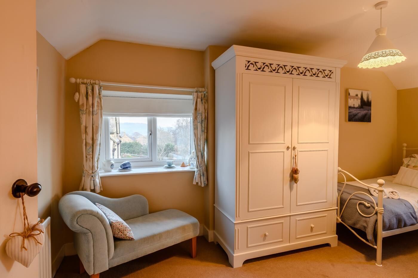 A bedroom with a bed, a wardrobe, a window with curtains, and a radiator.
