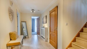 A hallway with a wooden bench, a mirror, and a staircase. - 3 Bed in Southwold (oc-s27203) (Reydon)