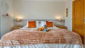 A neatly made bed with a fluffy blanket, two pillows, and a tray with bread and a coffee pot. - 3 Bed in Southwold (oc-s27203) (Reydon)
