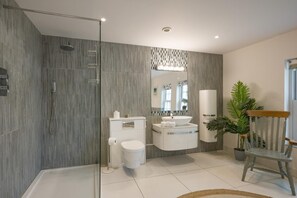 Une salle de bain moderne équipée d’une douche, de toilettes, d’un lavabo et d’un miroir.